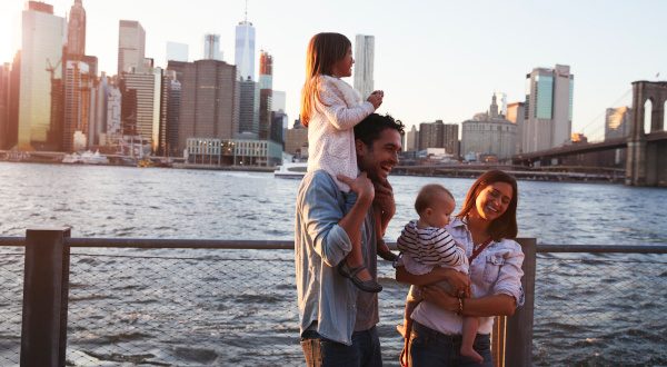 Young family with daughters standing on quayside, side view